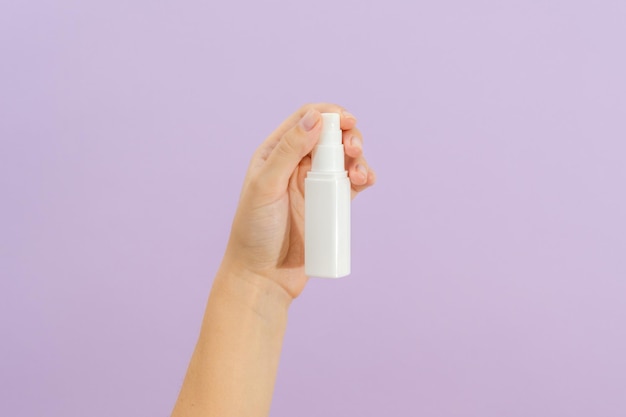 Cosmetic cream battle in womans hand on light lilac background Beauty concept Packaging tube for cosmetic products