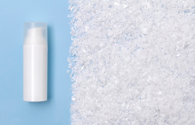 Cosmetic cream in a bottle on snowy table