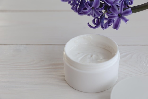 Cosmetic cream and flower on a white background