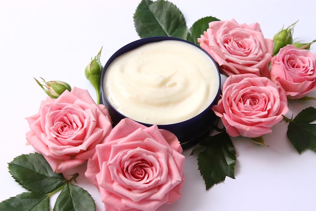 Cosmetic cream and flowers on a colored background closeup