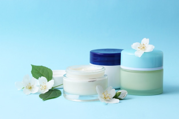 Cosmetic cream and flowers on a colored background closeup