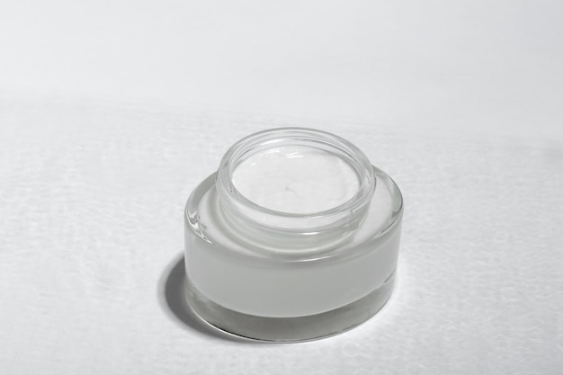 Photo cosmetic cream or mask in a glass jar with hard shadows from the leaves on a white background natural organic care for face and body skin view from above