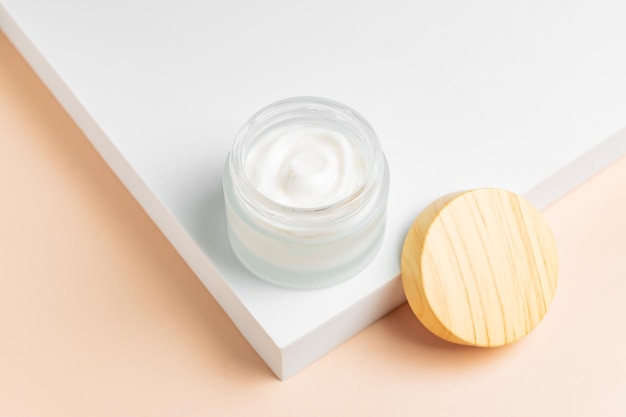 写真 cosmetic cream or moustirizer frosted glass open jar onwhite podium background open round glass jar with aesthetic swirls cream top view flatlay copy space