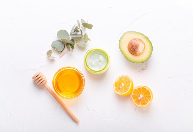 Crema cosmetica con ingredienti biologici naturali miele di avocado limone ed eucalipto foglie su sfondo di pietra bianca cosmetici e cura della pelle organica per il concetto di prodotto per la cura del viso e del corpo flat lay xa