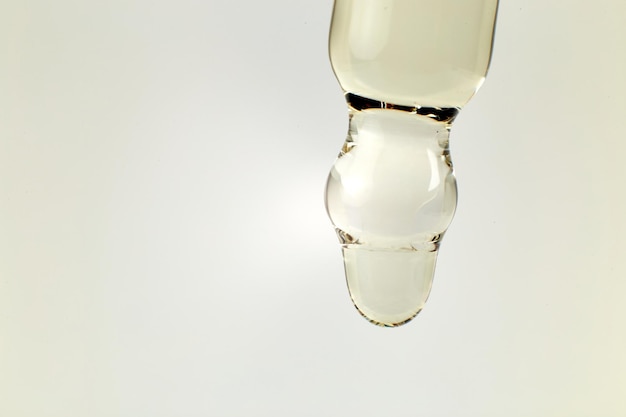 Косметическое или эфирное масло капает из стеклянной капельницы