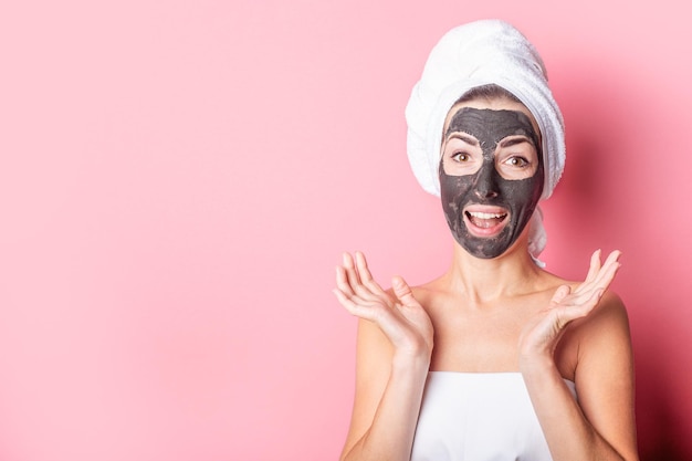 Procedure termali per maschera facciale cosmetica ragazza con maschera sul viso su sfondo rosa