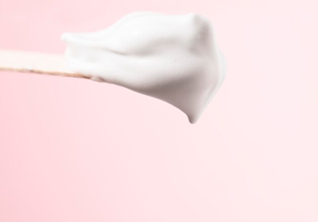 Cosmetic foam cream on a wooden spatula macro A sample of a white liquid beauty product