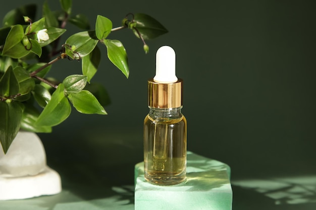 Косметические масла из стеклянной бутылки на зеленом фоне подиума Spa Natural Serums Dropper Bottle MockUp