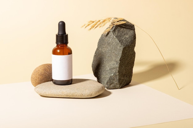 Cosmetic glass bottle with dropper for essential oils, creams and serum next to stone with hard shadow. The concept of a beauty salon and natural cosmetics.