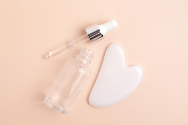 Cosmetic glass bottle with dropper and guasha The concept of a beauty salon and natural cosmetics