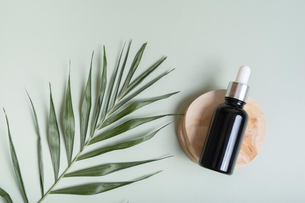 Cosmetic glass bottle with pipette on wooden slice top view flat lay on colored background with nature decoration