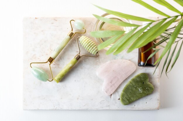 Cosmetic items and oil on a marble board Cosmetics on the background of a palm leaf View from above