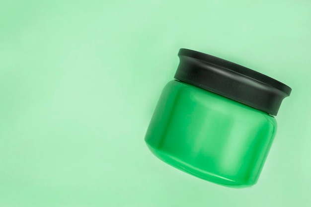 Cosmetic jar on green background