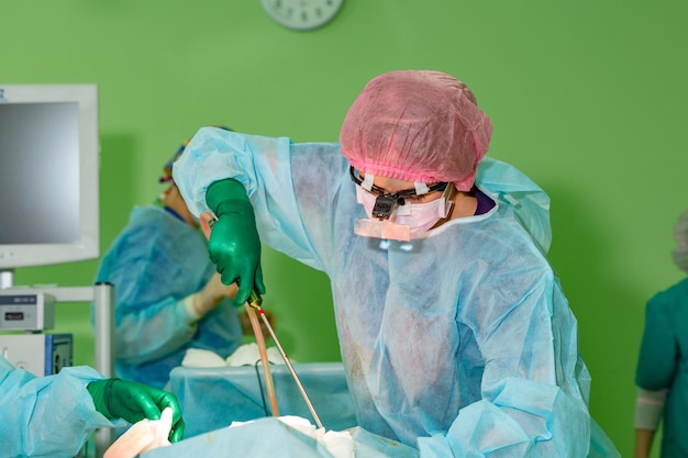 Cosmetic liposuction surgery in actual operating room group of surgeons working with cannula