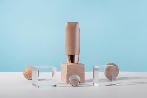 Cosmetic liquid foundation nude cream tube mockup on acrylic and wooden block podium pedestal Beige concealer base cosmetics product mock up on blue backdrop Skincare beauty primer cc corrector