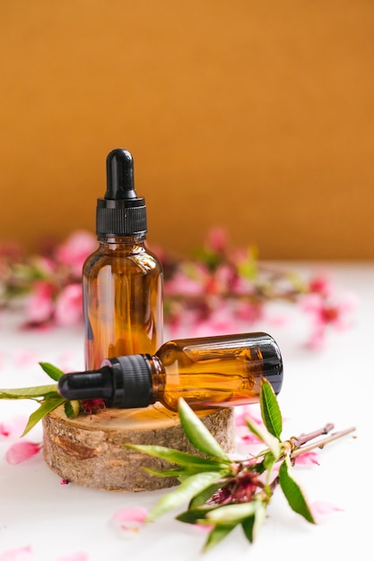 Cosmetic oil in a container with an eyedropper stands on a podium made of a cut tree. Essential oil for aromatherapy.Composition of natural materials.