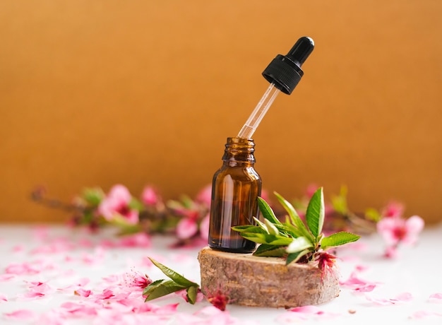 Cosmetic oil in a container with an eyedropper stands on a podium made of a cut tree. Essential oil for aromatherapy.Composition of natural materials.