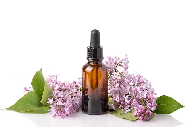 Cosmetic oil in lilac flowers. Cosmetics for body and face skin care. On white background. Isolate.