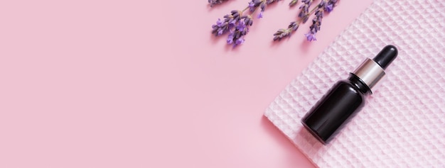 Cosmetic oil in pipette bottle with lavender flowers on colored background Top view Flat lay