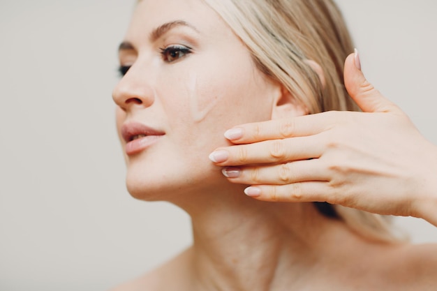 Cosmetic oil royal jelly applying on face of young adult woman