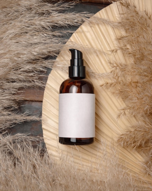 Cosmetic one pump bottle on dried palm leaf near pampas grass top view Label Mockup