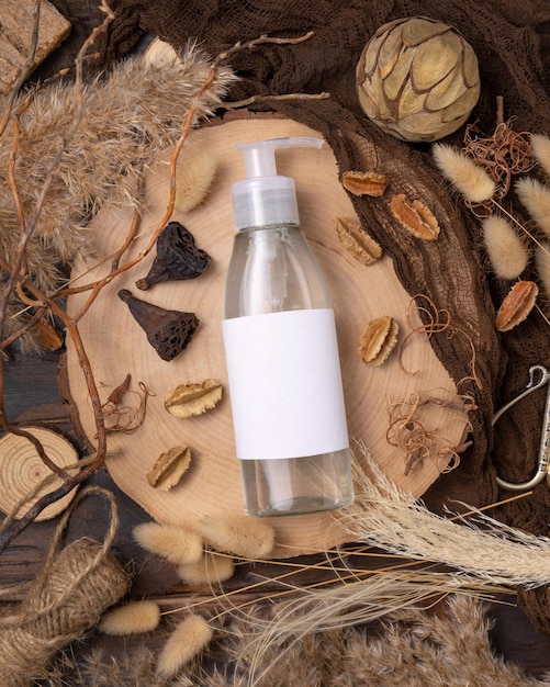 Flacone cosmetico con una pompa su legno vicino a decorazioni boho naturali vista dall'alto label mockup