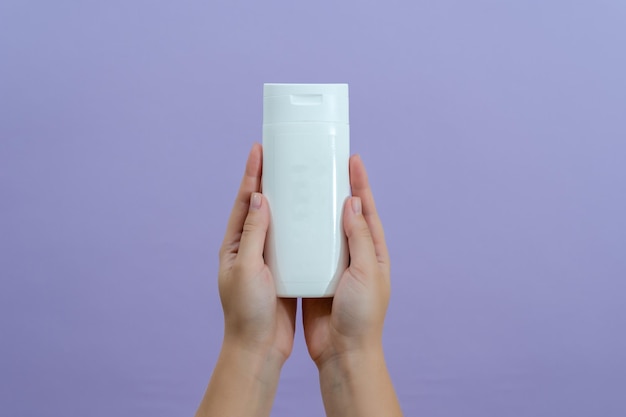 Cosmetic packaging tube in womans hand on lilac background
beauty concept tube for cosmetic products