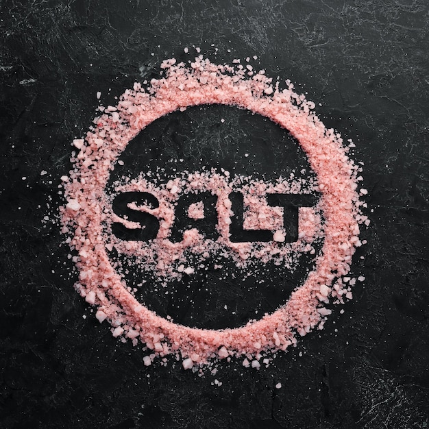 Косметическая розовая соль с надписью SALT На фоне черного камня Спа-процедуры Вид сверху Свободное место для текста