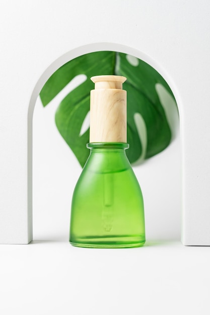 Cosmetic pipette bottle on the background of tropical monstera leaves. Nourishing or moisturizing serum, essence. Blank, unbrnded mockup. Home and salon care for hands, face, body or hair.