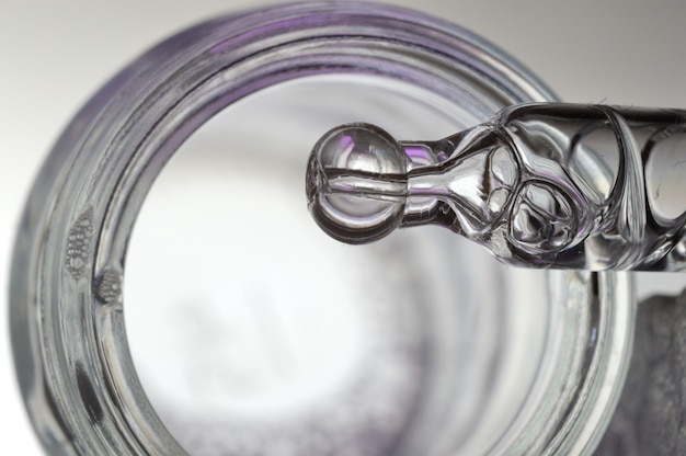 a cosmetic pipette filled with a bubbling liquid and a bottle. close-up.