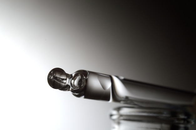 a cosmetic pipette with a liquid collected in it from a bottle. close-up.