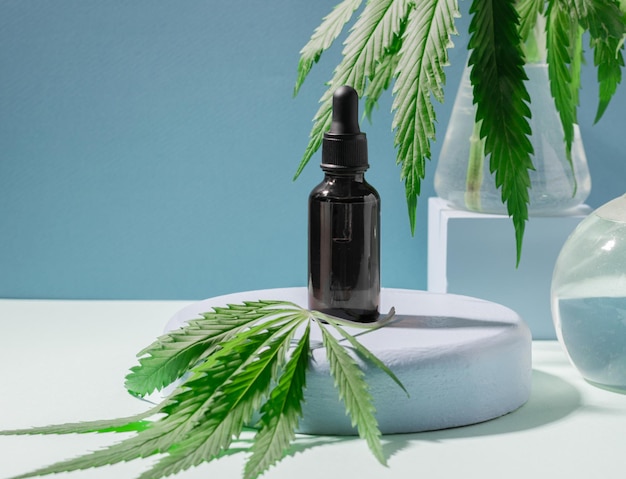 Cosmetic product oil serum from hemp sbd on a creative podium\
bottle with pipette blue background