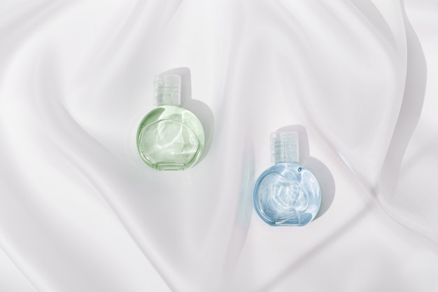 Cosmetic product in transparent plastic bottle with beautiful shadows on white silk cloth texture