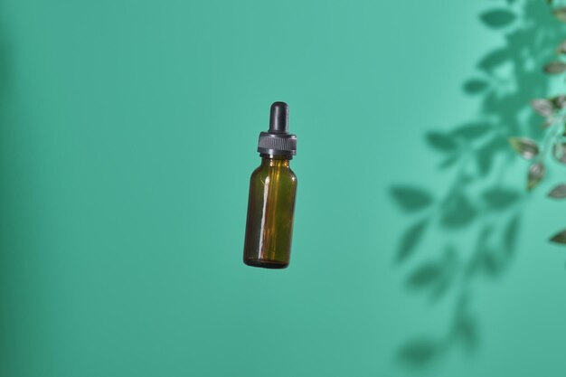 Prodotto cosmetico in tubo di vetro bottiglia lozione idratante antietà olio essenziale per il viso o siero su sfondo verde con ombra leggera natura naturale biologico e concetto di bellezza per la cura della pelle