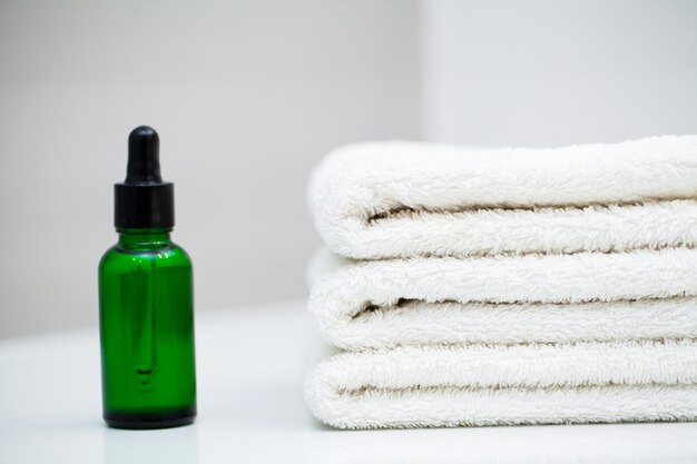 Cosmetic products and cotton towels on white wooden table in beauty salon