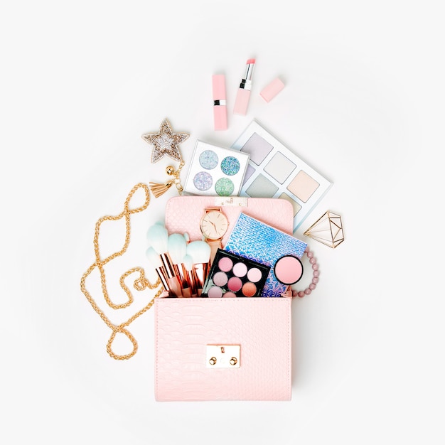 Cosmetic products flowing from Makeup bag on white background