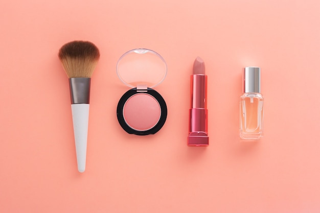 Cosmetic products on light coral background