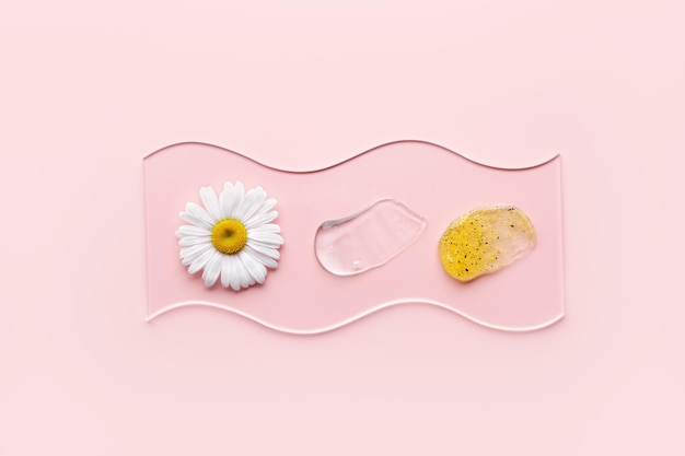 Cosmetic products with particles in glass slide on pink background Natural skincare samples with chamomile