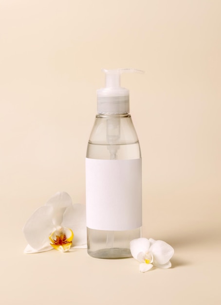 Cosmetic pump dispenser bottle near white orchid flowers on light beige close up Mockup