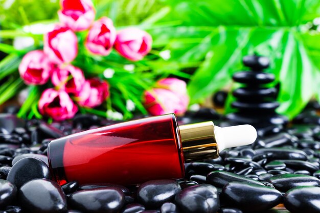 Photo cosmetic red bottle for essential oils on black stone