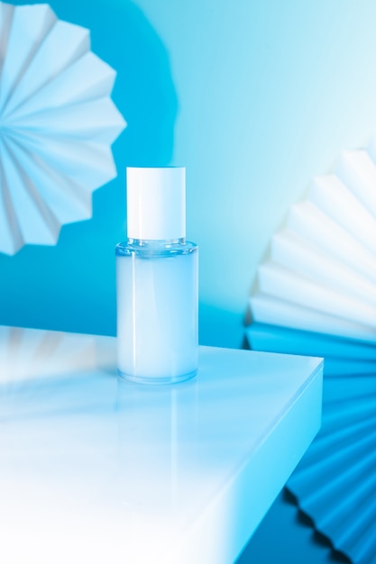 Cosmetic serum bottle on a white table, blue neon light, mock up