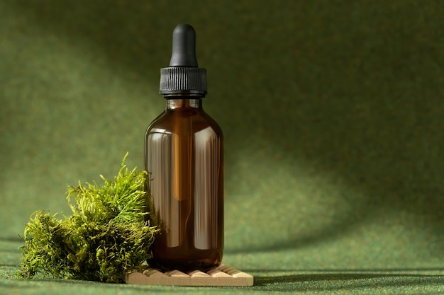 Flacone di siero cosmetico con pipetta su sfondo naturale verde