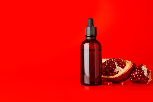 Cosmetic serum dropper bottle with pomegranate flavor on red background