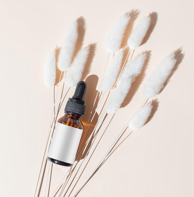 Cosmetic serum pipette dropper or organic essential oil for the face and body on beige background with hard shadows The concept of a beauty salon and natural cosmetics