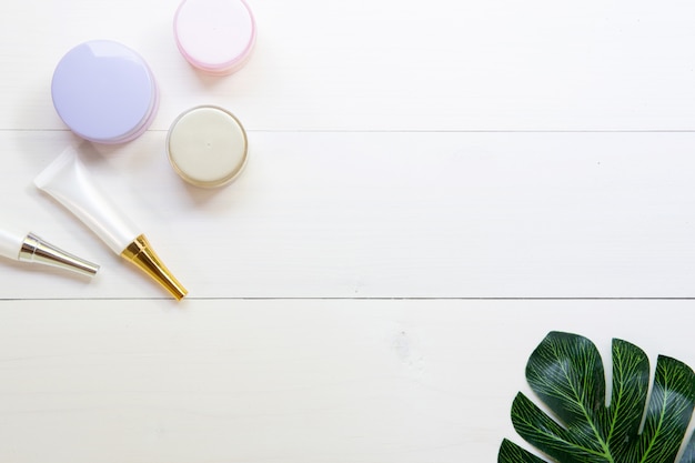 Cosmetic and skin care product and green leaves on white wood table