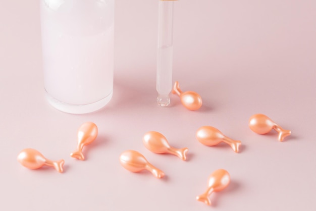 콜라겐 에센스가 포함된 화장품 스킨케어 얼굴 캡슐 핑크색 액체 제품이 포함된 투명한 유리 병 스포이드 천연 모이스처라이저 및 주름 방지 화장품 개념