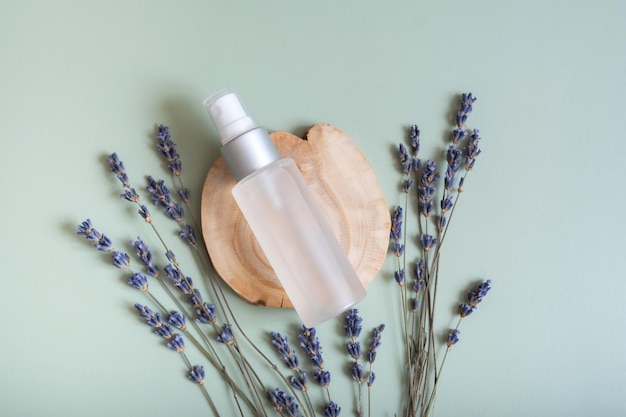 Foto flacone spray cosmetico su fetta di legno vista dall'alto piatto su sfondo colorato con fiori di lavanda concetto cosmetico naturale