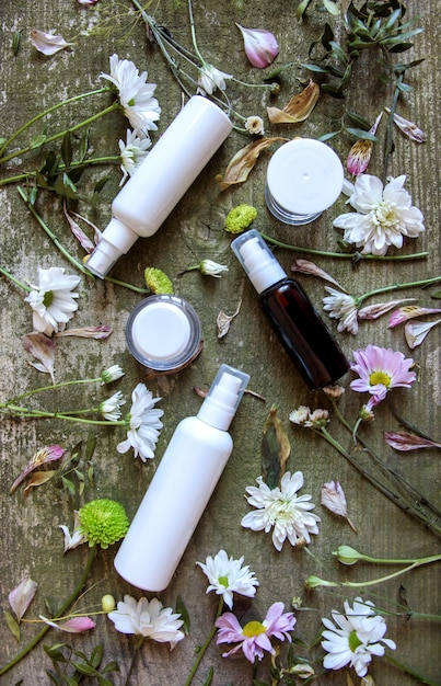 Cosmetic spray dispenser and flowers on a wooden background