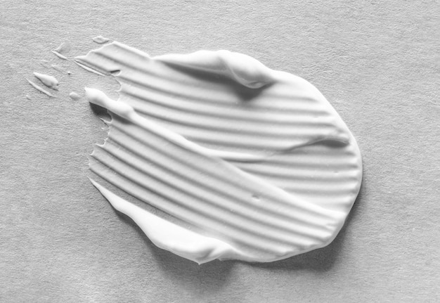 Foto maschera di crema bianca cosmetica macchia di consistenza isolata su sfondo di consistenza di carta grigia