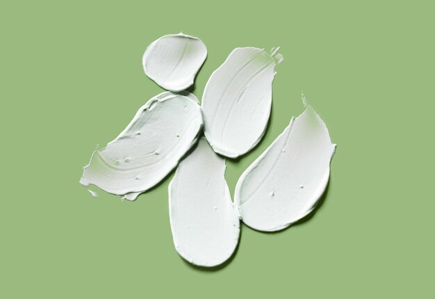 Photo cosmetic white cream balm mask texture smudge isolated on green background